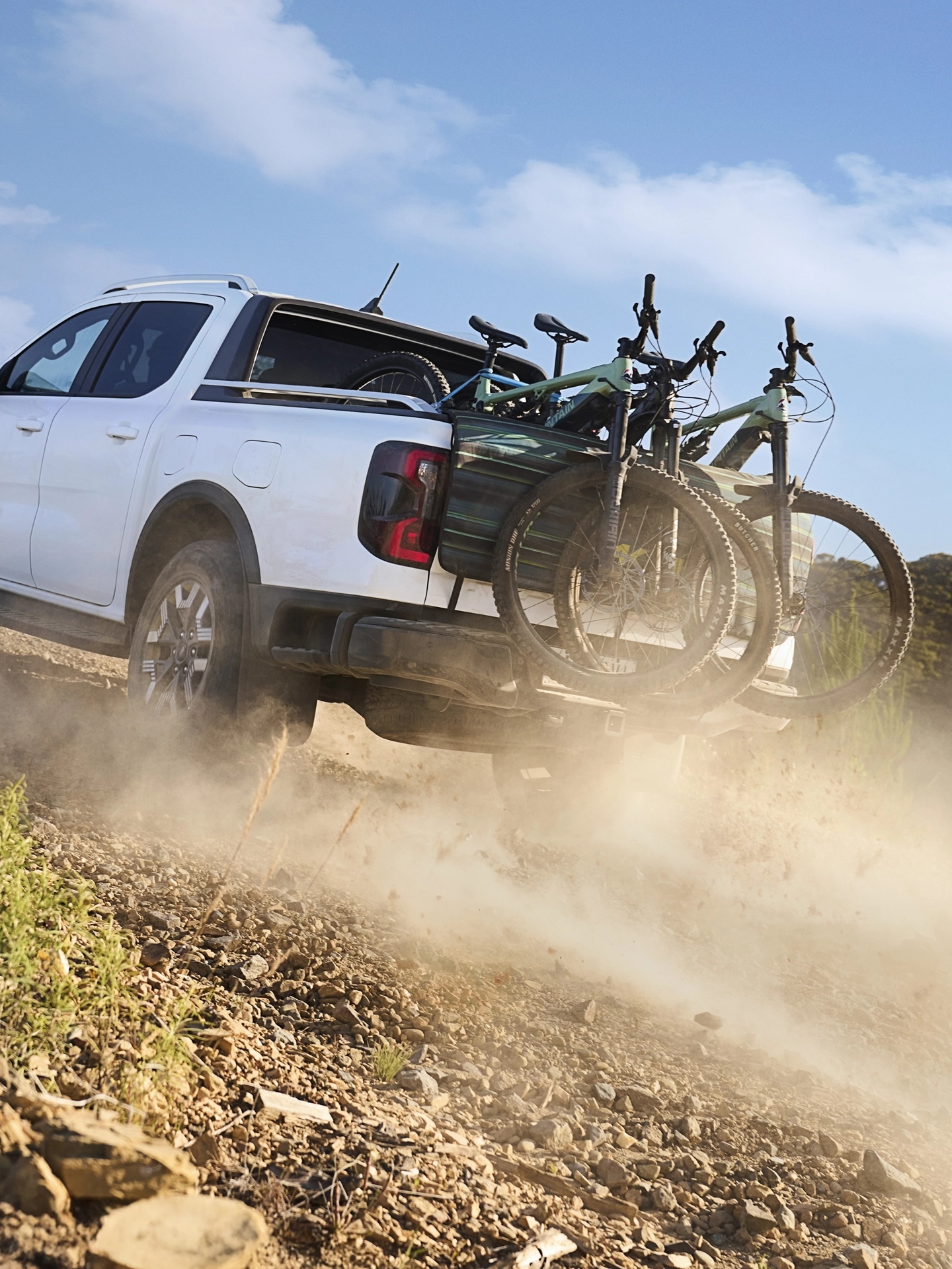 Le Ford Ranger conduit sur un terrain accidenté avec des vélos de montagne dans la caisse du camion.